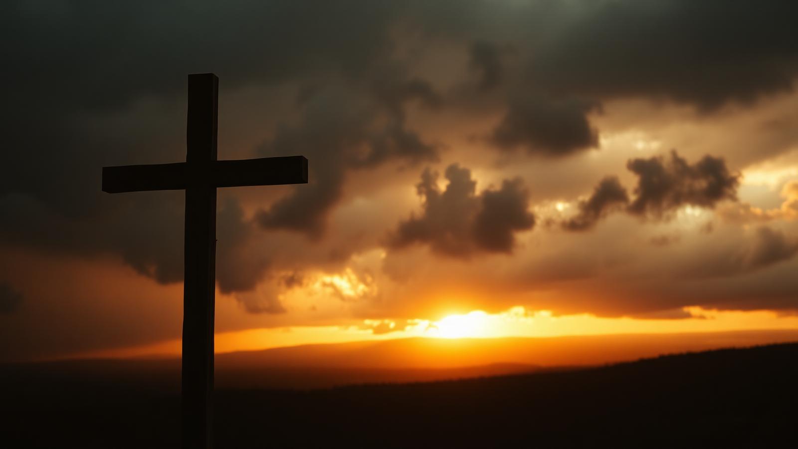 A wooden cross on a hilltop silhouetted against a breaking dawn